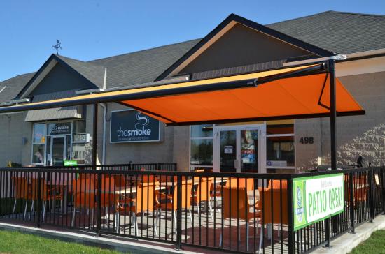 Exterior of The Smoke Restaurant. Showcasing their outdoor patio with orange chairs and canopy.