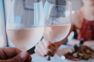 Two glasses of rose wine clinking together as a couple cheers over their dinner date