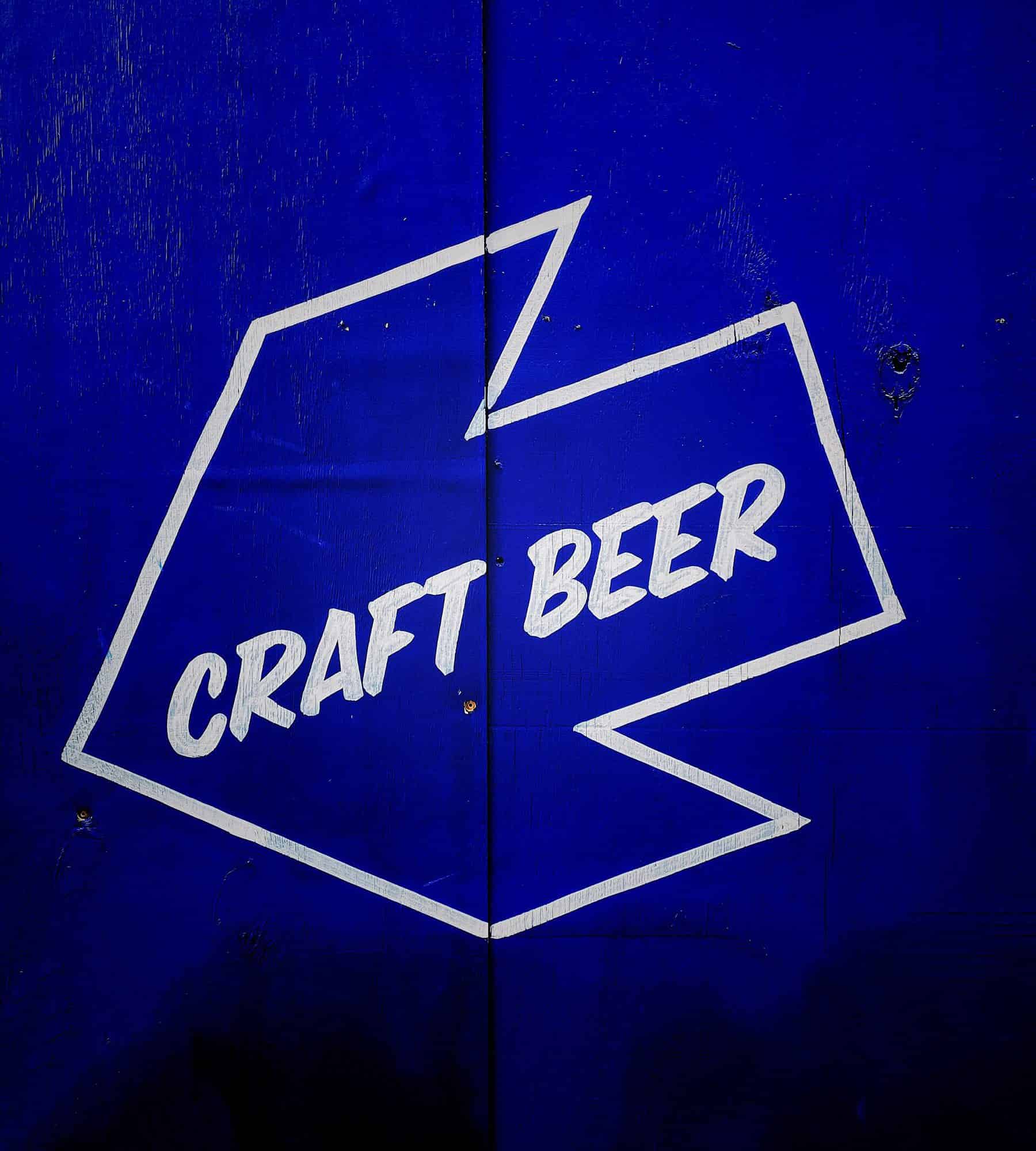 white neon sign that has the words craft beer inside it with a blue background