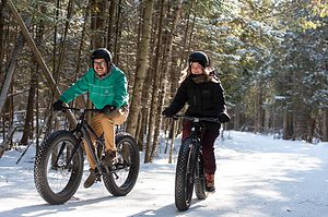 a man and woman fat biking in a forest