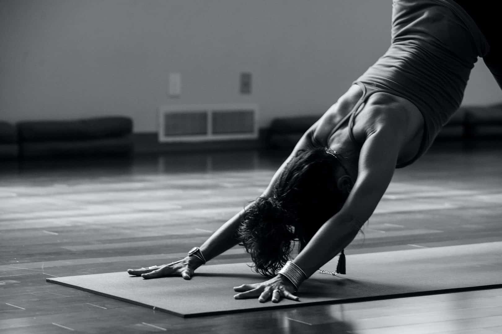 Black and white photo of woman doing downward dog on a yoga mat