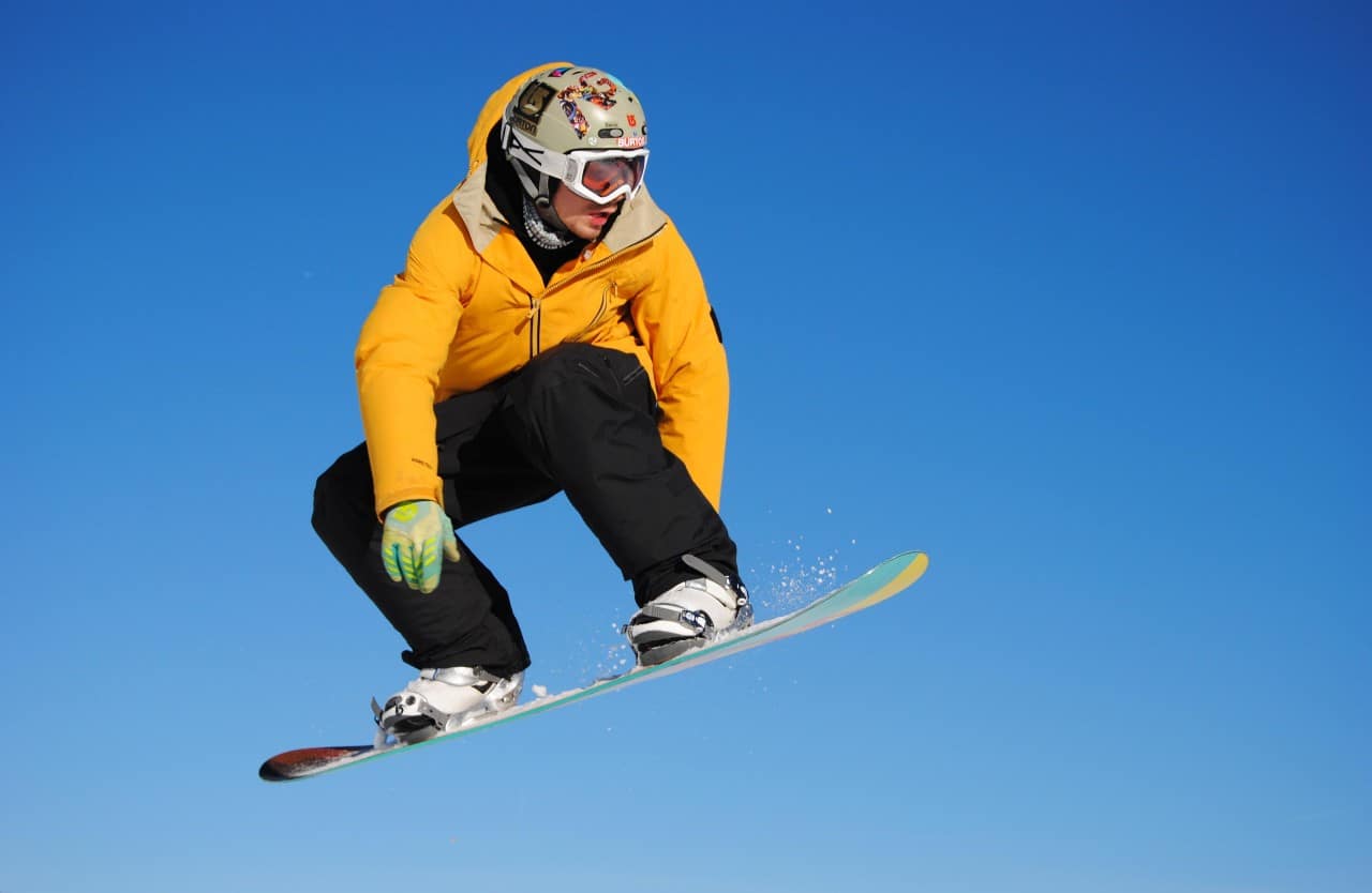 Man on a snowboard doing a jump trick, flying through the air