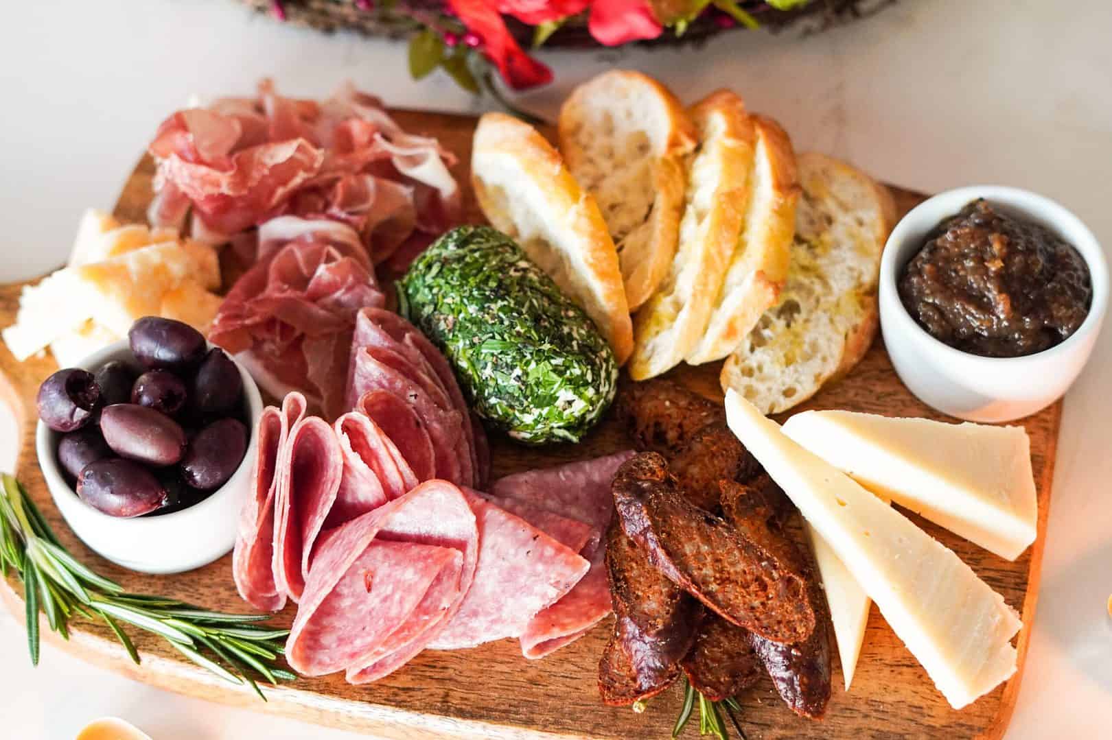 charcuterie board with cheeses, meats, olives, dips and bread